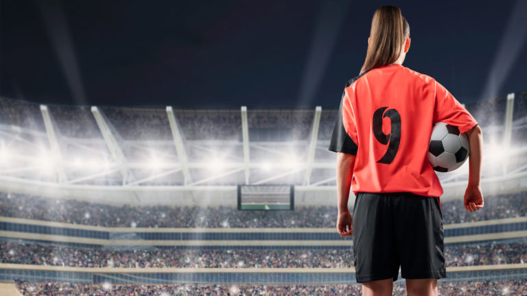 female football player in red uniform holding ball on full stadium on background